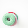 Stack of donut shaped teether toys multi colored with light green donut laying on top