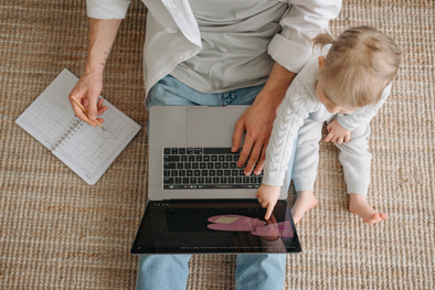 Mom next to a baby with laptop on her lap