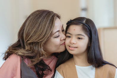 portrait-of-mother-kissing-her-special-needs-daughter