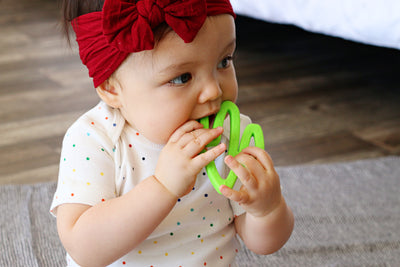 baby chewing on lime colored cactus teething toy