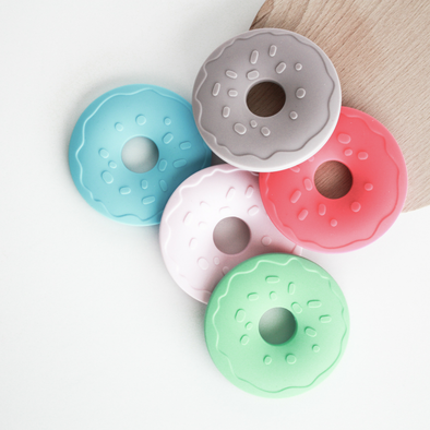 Pile of 5 donut teething rings blue pink gray green and dark pink 