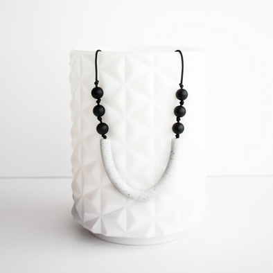 Sawyer teething necklace. White  long bead in middle, three small black beads on each side.