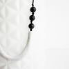Sawyer teething necklace. White  long bead in middle, three small black beads on each side.