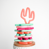 Cactus shaped teething toys stacked in multi colors. Top one is coral and is standing 