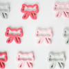 Flat lay of bow shaped pink gray and coral teething toys