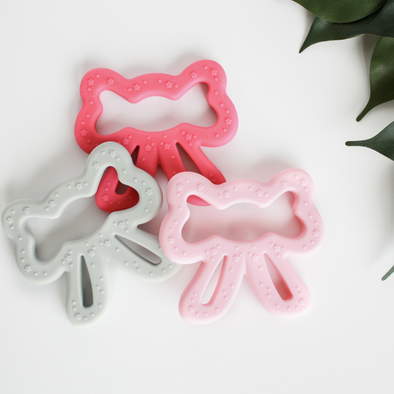 Three bow shaped teething toys gray pink and coral