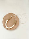 Sawyer teething necklace. Cream colored long bead in middle, three small taupe beads on each side.