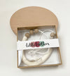 Sawyer necklace inside box packaging with window. Little Teether band around box 