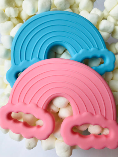 One cyan and one taffy rainbow silicone teething toys. Marshmallow cloud background. 