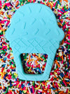 One cyan blue ice cream teething toy on top of colorful sprinkles. 