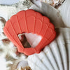 Coral seashell Teether, shell and sand background. 