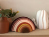 Silicone rainbow stacker . Muted brown, tans, oranges, pinks. Next to plant and cactus decor
